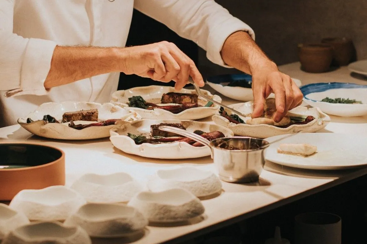 Cocinero emplatando varios platos en el pase de la cocina