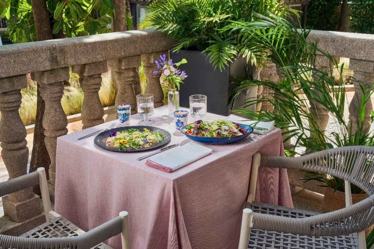 Terraza del hotel con mesa puesta y dos ensaladas entre plantas