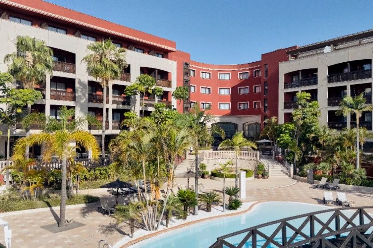 Fachada y piscina del hotel Barceló Marbella rodeada de palmeras