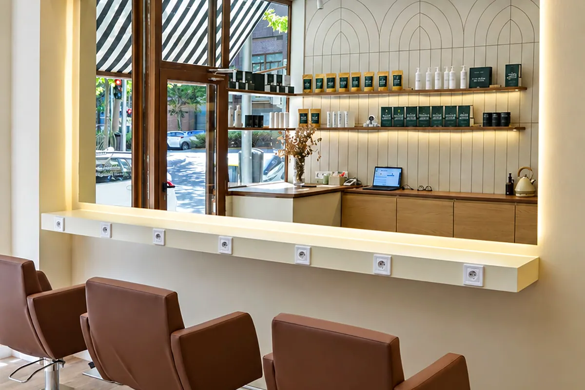 Interior del centro capilar Barros de la India en Madrid con sillones marrones y espejo