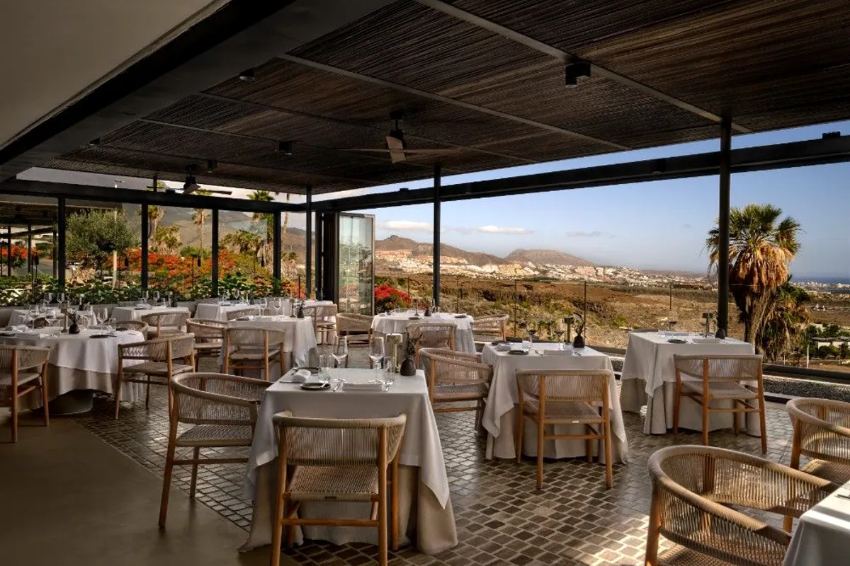 Comedor del restaurante Bonfire con mesas vestidas y vistas al mar y la montaña