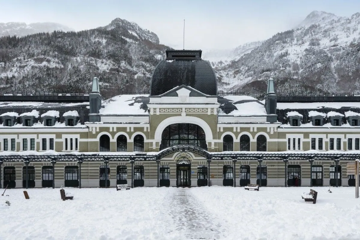 Fachada nevada de la antigua estación de Canfranc, hoy hotel, con el Pirineo detrás