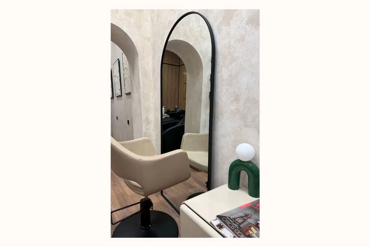 Interior del salón de Chema Hair en Chamberí, con sillón beige y espejo de arco