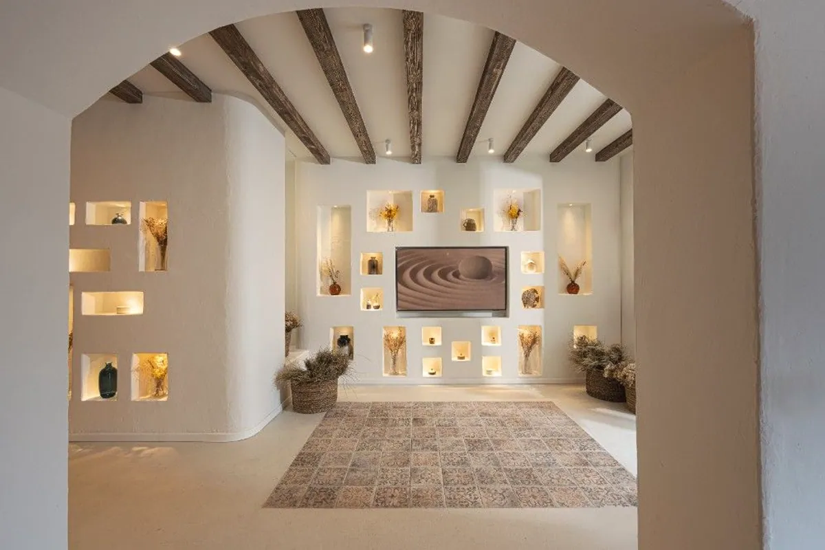 Sala blanca con hornacinas iluminadas y vigas de madera en el hotel de Conil