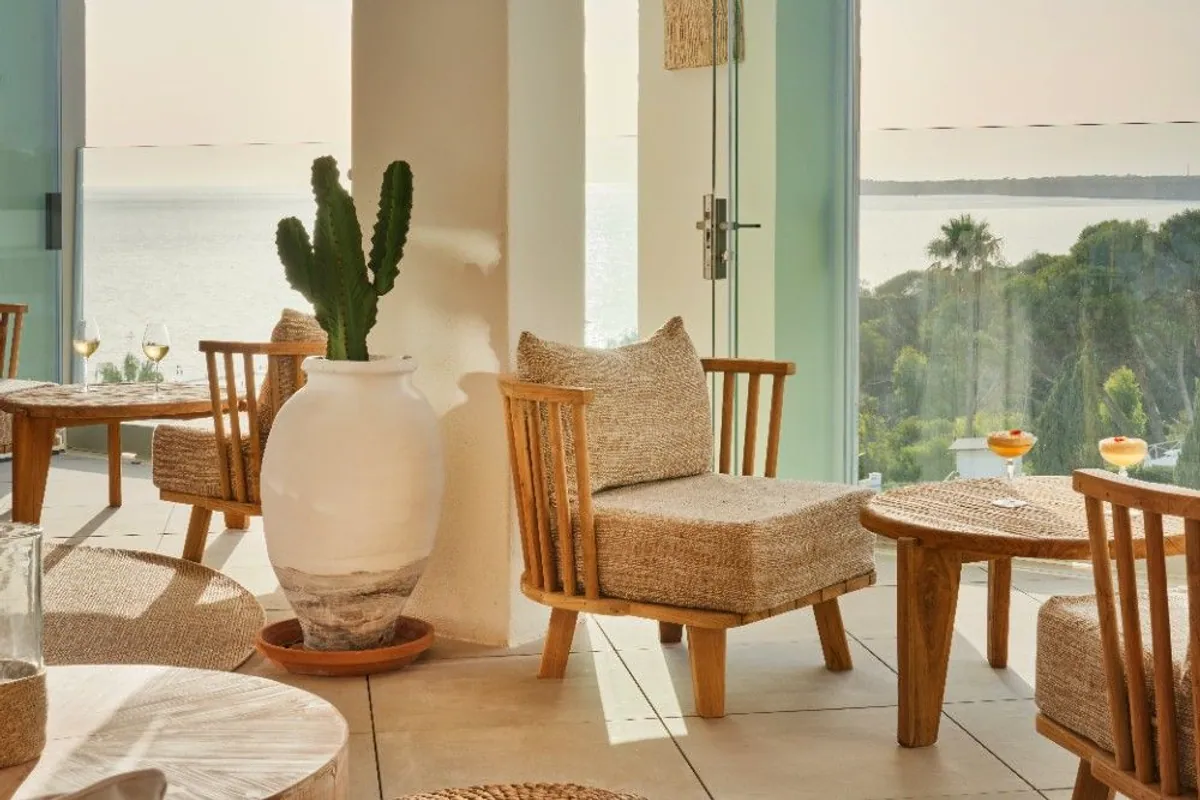 Terraza con butacas de fibra natural, cactus y vistas al mar al atardecer