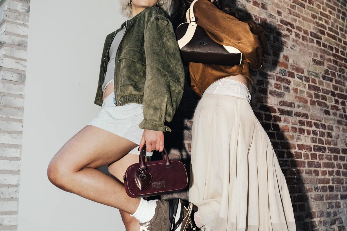 Chica sentada en un muro con sneakers FILA y bolso bowling