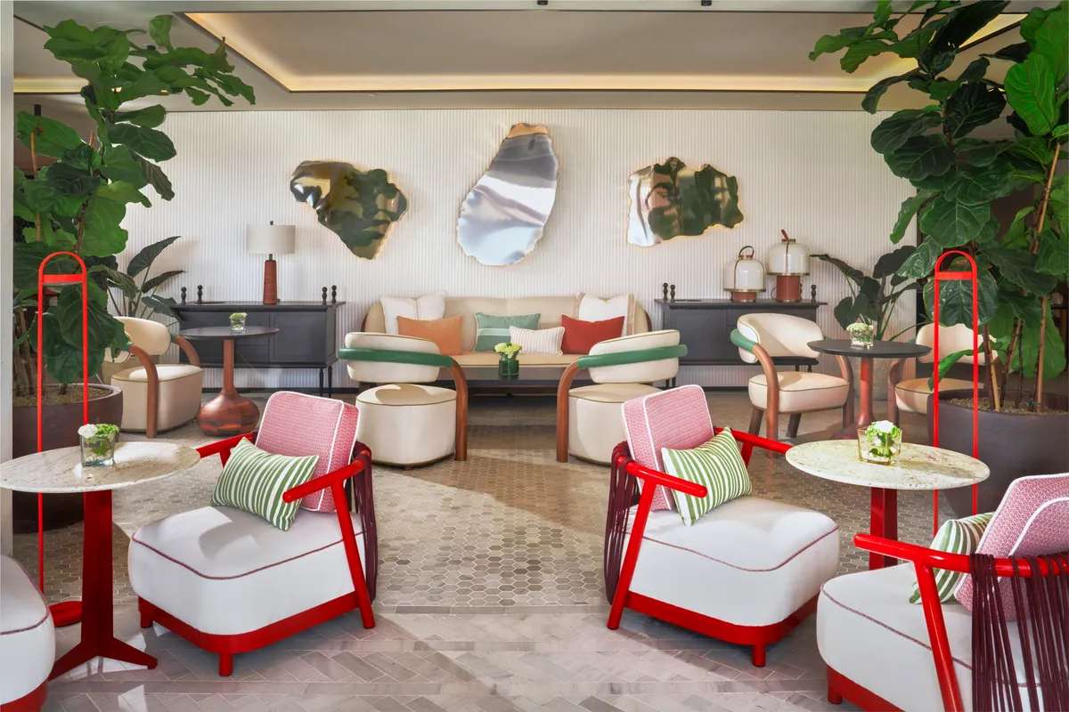 Salón del hotel El Fuerte Marbella con butacas rojas, sofás blancos y plantas grandes
