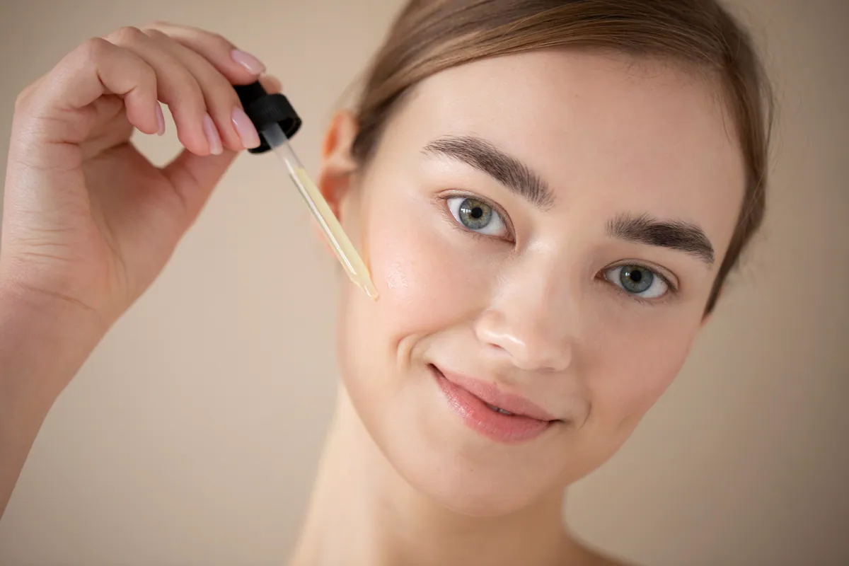 Mujer aplicándose un sérum facial con la piel luminosa