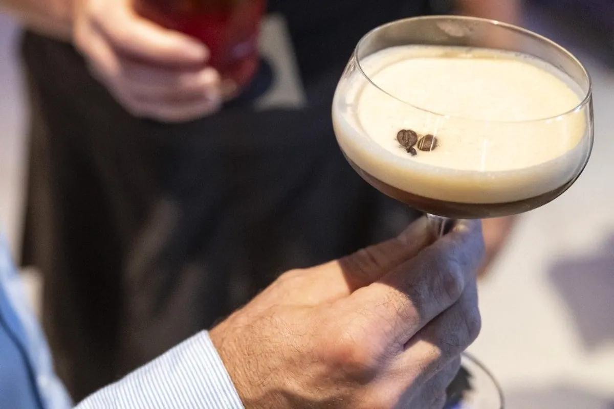 Cóctel de café con espuma y granos encima sostenido en una copa