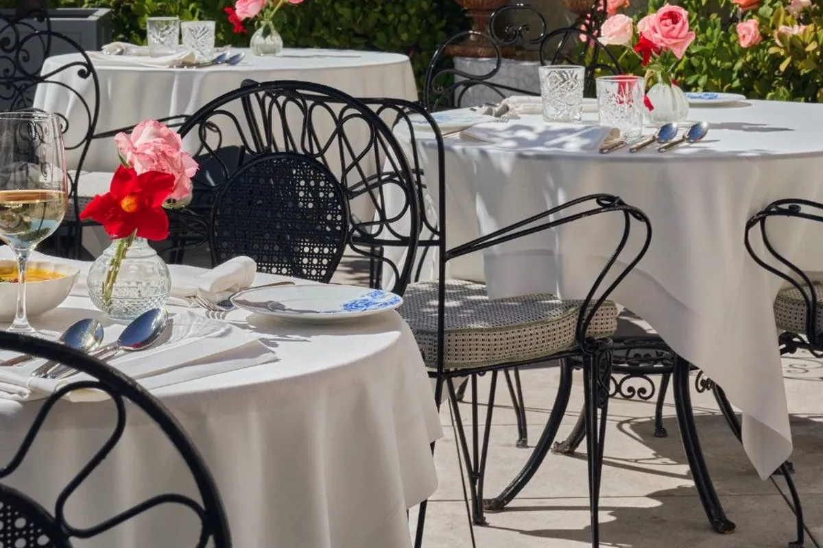 Mesas con mantel blanco en la terraza del Hotel Heritage Madrid rodeadas de rosales