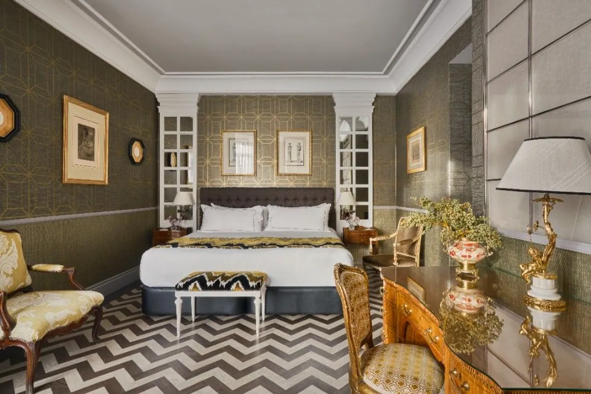 Habitación del Hotel Heritage Madrid con papel pintado dorado y suelo de espiga