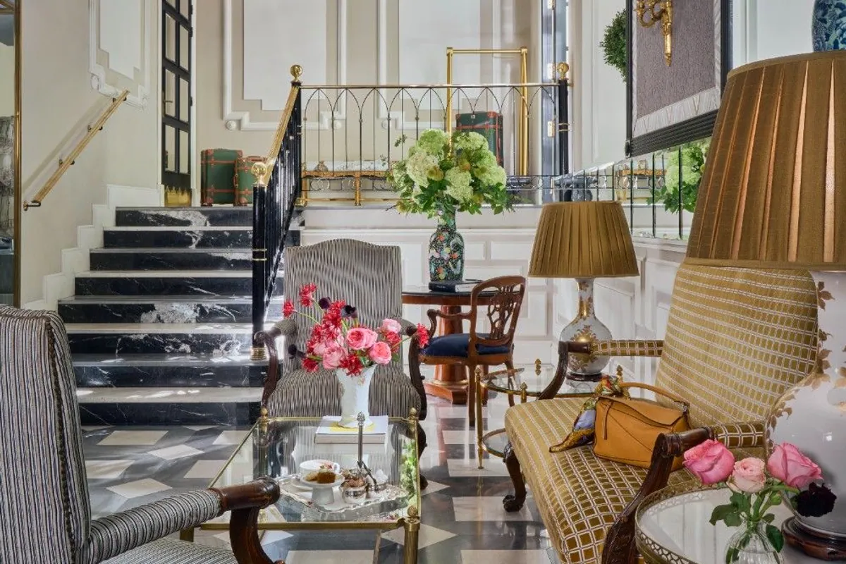 Salón del Hotel Heritage Madrid con suelo de mármol en damero y escalera