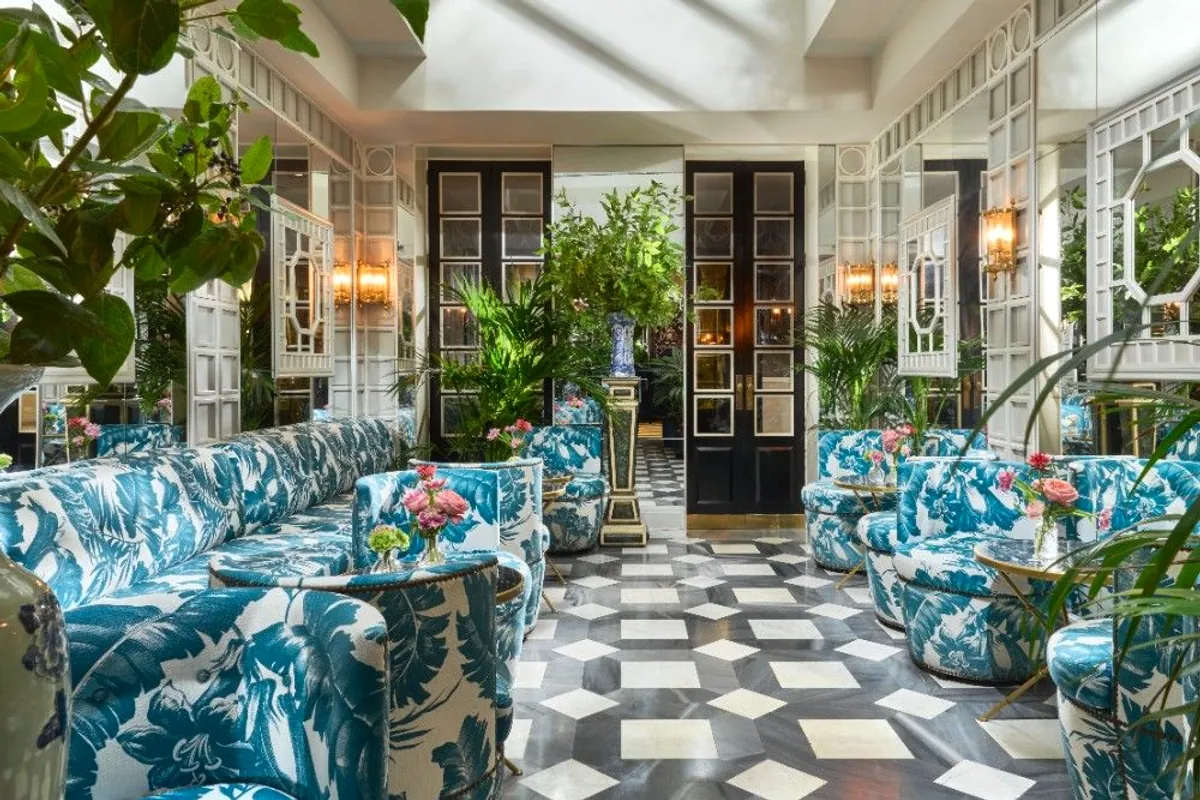 Salón del hotel con suelo de mármol a cuadros y butacas estampadas en azul