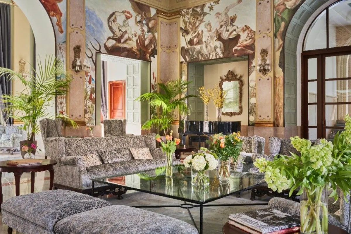 Salón histórico del hotel Santa Catalina con frescos, piano de cola y plantas