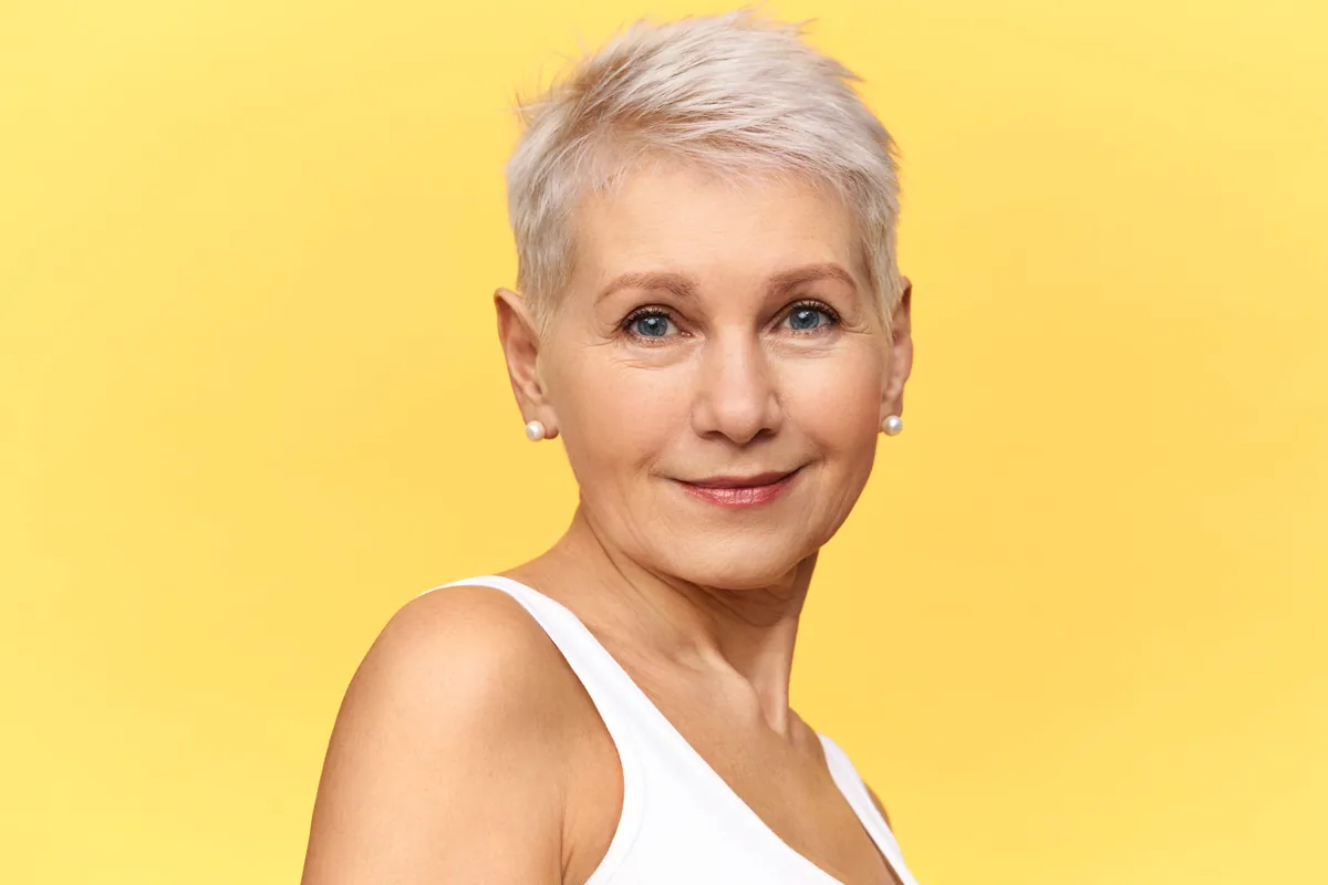 Mujer con el pelo corto y canas cuidadas sonriendo