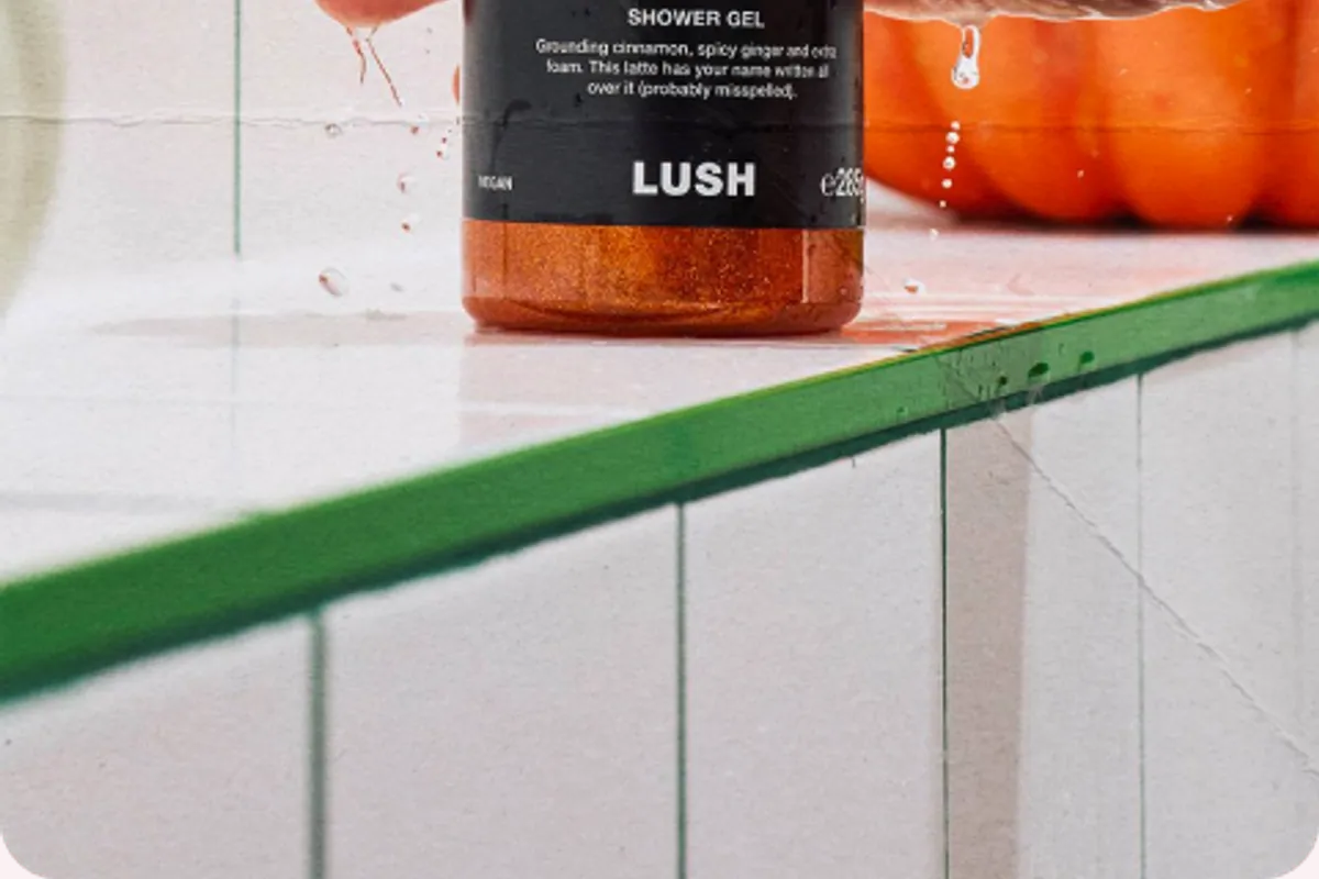 Gel de ducha Cinnamon Spiced Latte de Lush sujetado en una ducha con una calabaza detrás