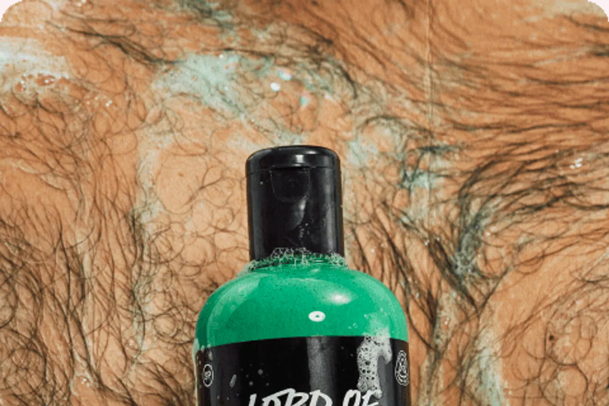 Bote verde del gel de ducha Lord of Misrule de Lush con espuma en una mano