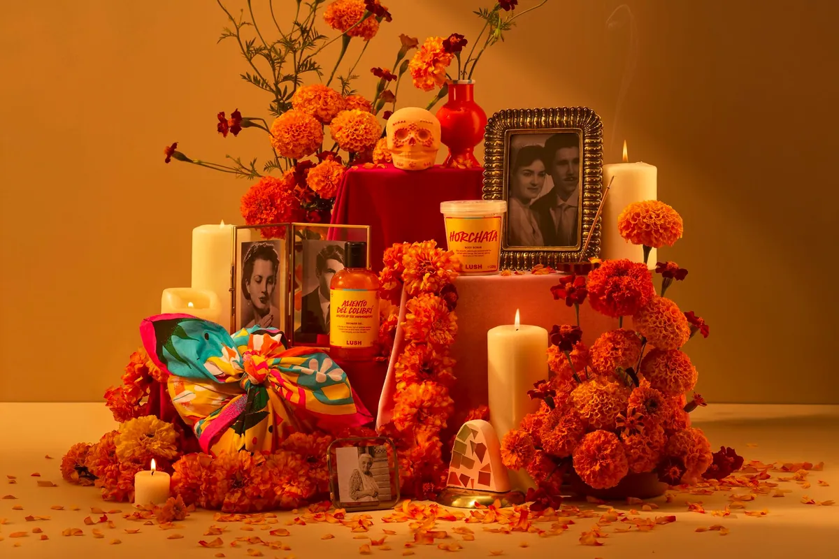Altar de Día de Muertos con los productos de Lush, flores de cempasúchil, velas y retratos antiguos