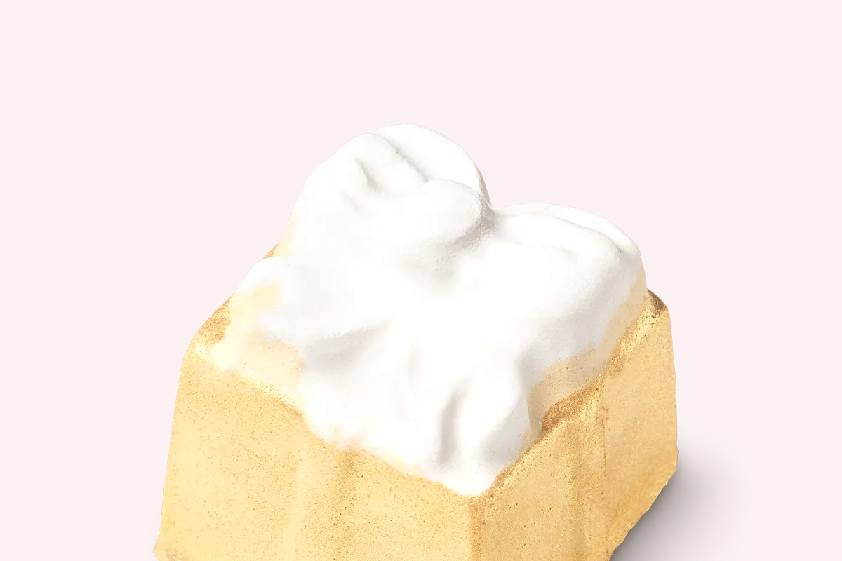 Bomba de baño dorada de Lush con la parte superior blanca
