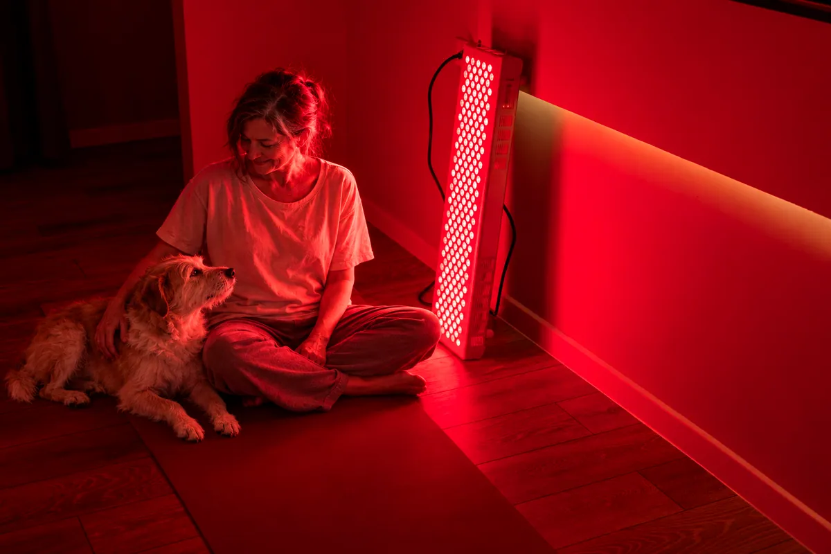 Ambiente de luz roja cálida en casa por la noche, con una mujer y su perro