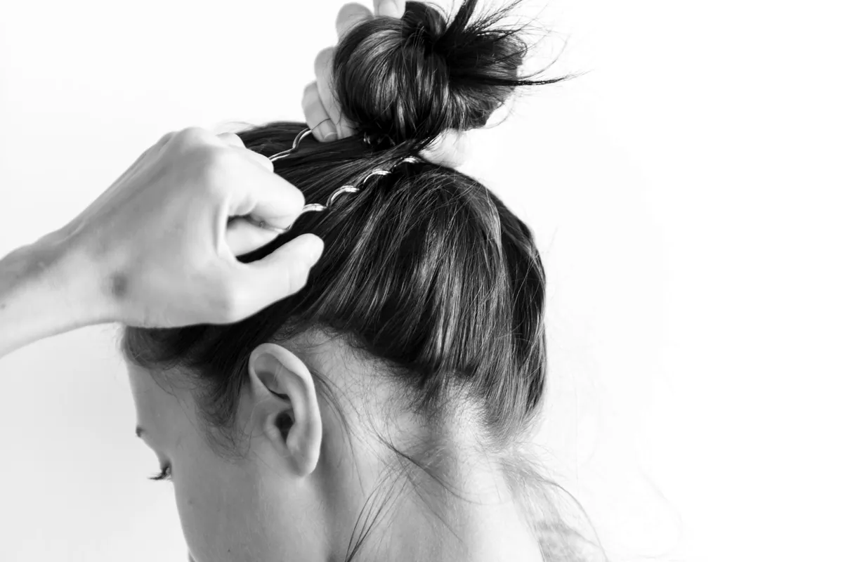 Mujer recogiéndose el pelo en un moño alto