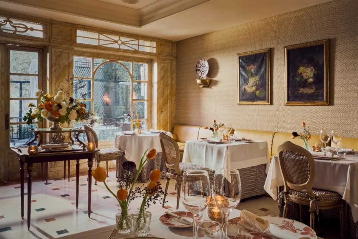 Comedor de El Jardín de Orfila con mesas vestidas de blanco y ventanal al patio