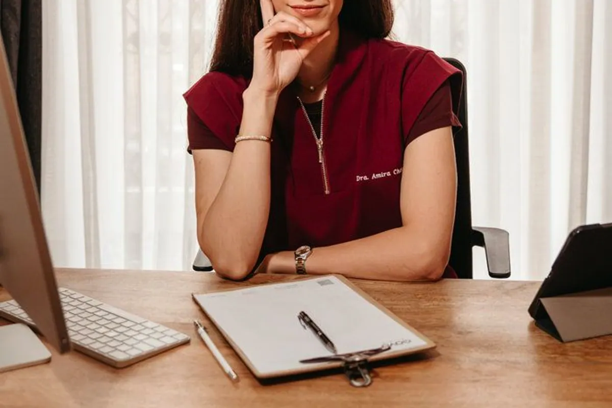 La doctora Amira Chehade sentada en su mesa de consulta con uniforme granate