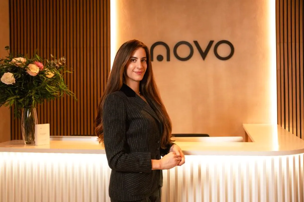 Mujer con traje junto a la recepción iluminada de NOVO Clinic