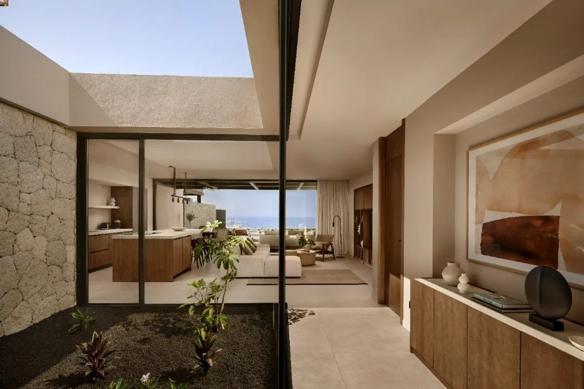 Patio interior ajardinado con salón y cocina al fondo en la villa