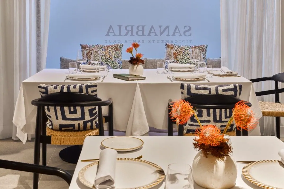 Sala del restaurante Sanabria con mesas vestidas de blanco y flores naranjas