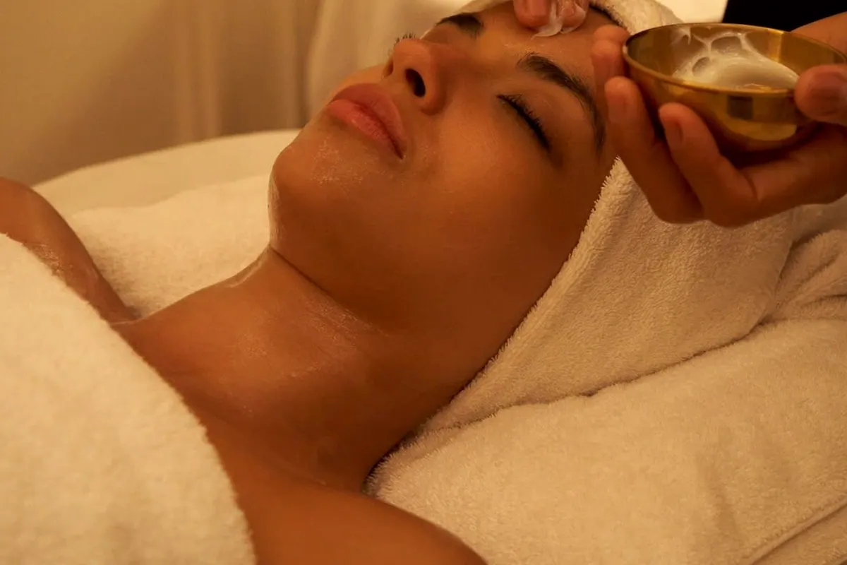 Terapeuta aplicando producto en la frente de una mujer durante un facial