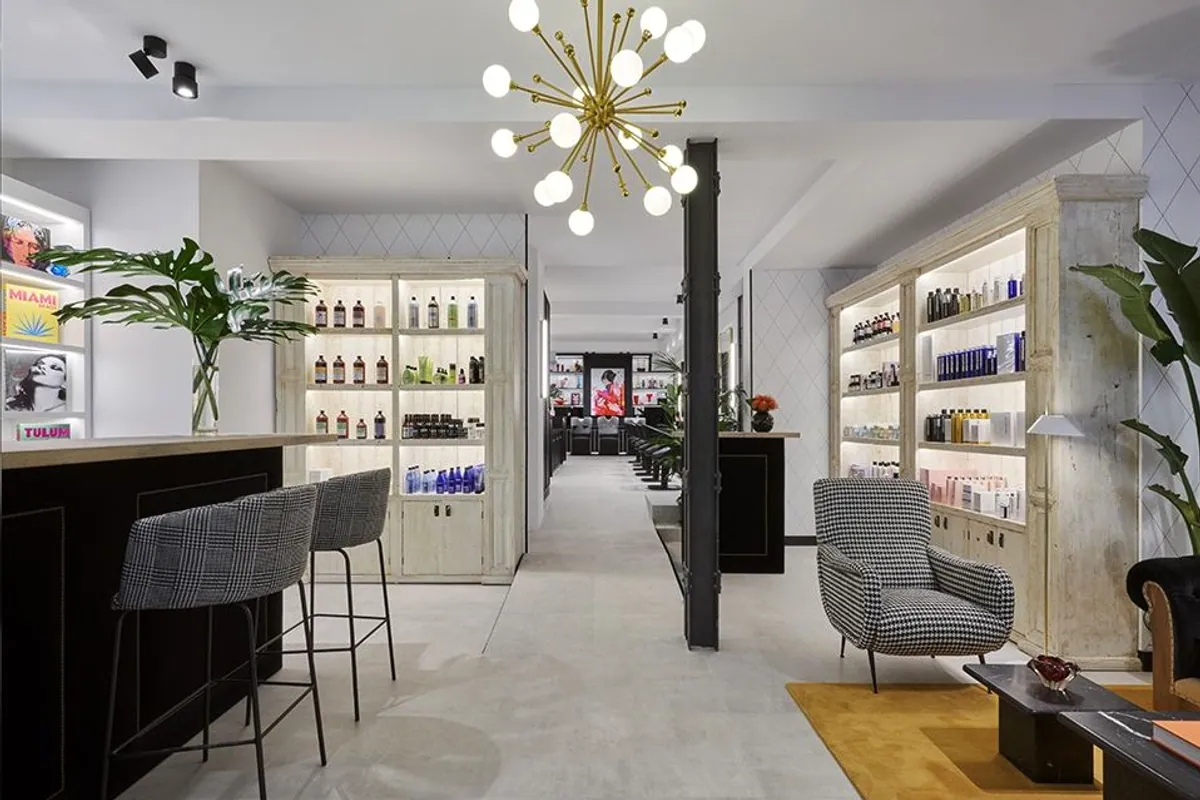 Interior del salón TBC Hair en Madrid con estanterías de producto y lámpara dorada