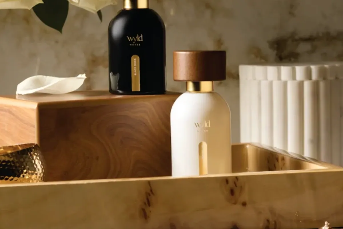 Los dos perfumes de Wyld Notes sobre una bandeja de madera con rosas blancas detrás